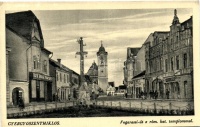 Gyergyószentmiklós, Gheorgheni; Fogarassi út a Római Katolikus templommal, Textil Áruház, Müller Gábor üzlete, gyógyszertár / street, church, shops, pharmacy (EK)