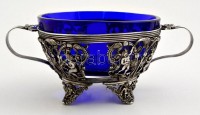 cca 1900 Puttós díszítésű, füles kínáló tál kék üvegbetéttel (hibátlan). ezüstözött áttört fém  / Silver plated metal tray with glass d: 16 cm